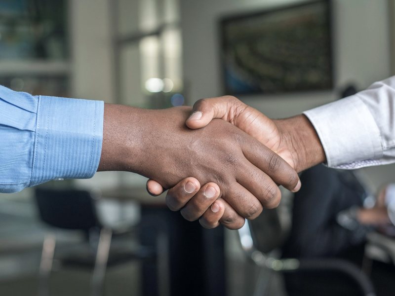 Two professionals shaking hands during a face-to-face client meeting